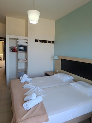 Una habitación de hotel con cama, mesita de noche, lámpara, armario y perchero.