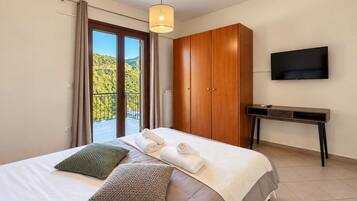 Ein Schlafzimmer mit einem Bett, Kissen, einem Kleiderschrank, einem Schreibtisch und einem Fernseher.