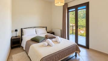Ein Schlafzimmer mit Bett, Nachttischen, einer Lampe, einem Fenster mit Aussicht und einem Balkon.