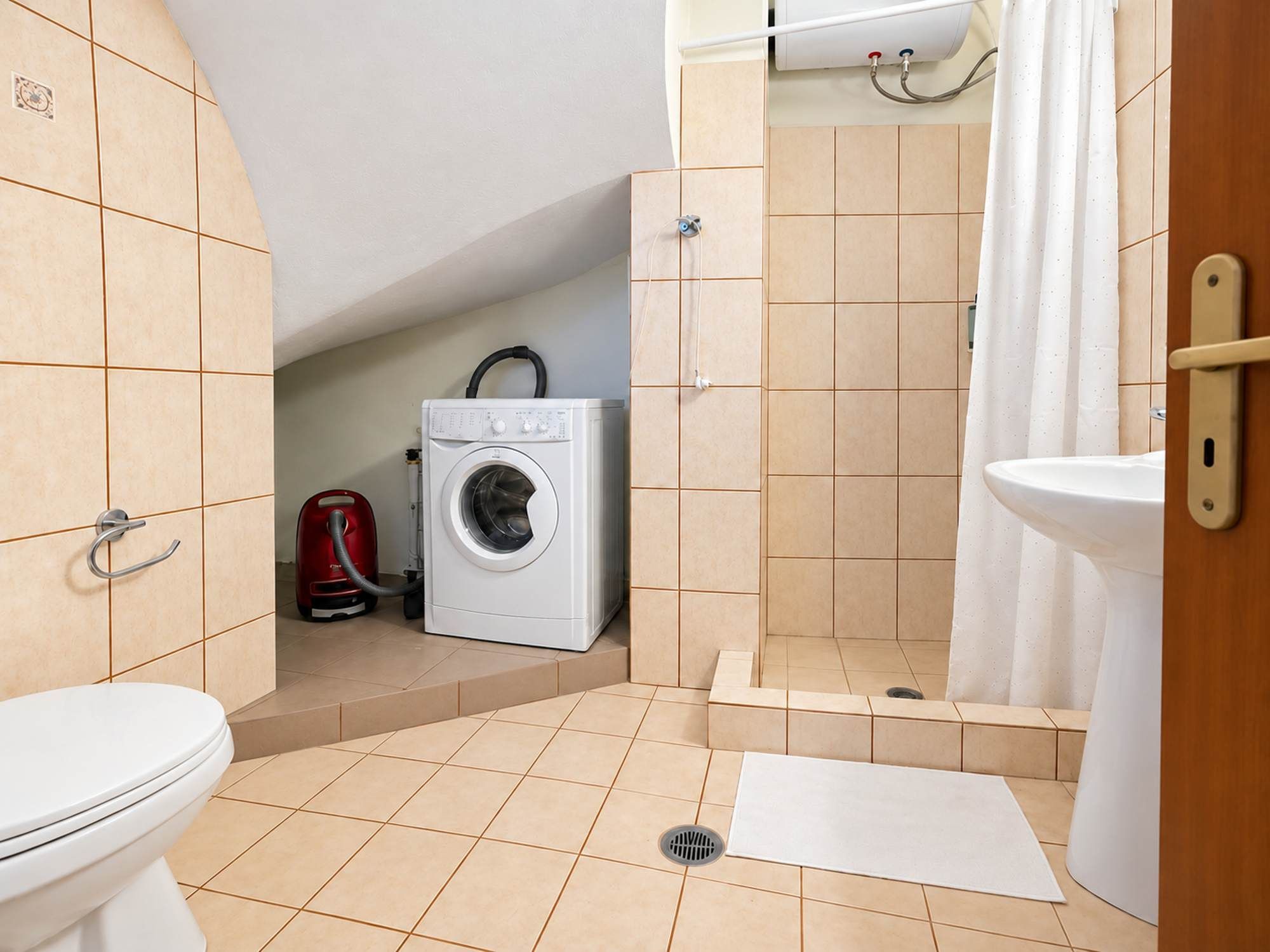 Ein kleines Badezimmer mit Toilette, Waschmaschine, Dusche und Waschbecken.