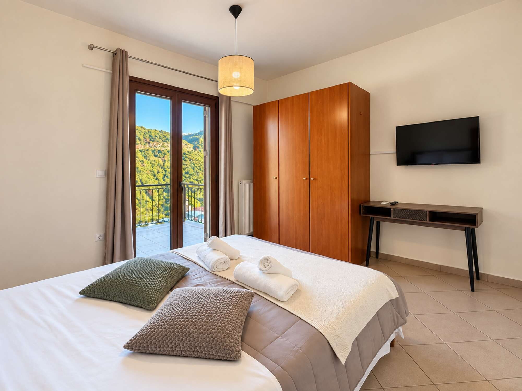 Une chambre à coucher avec un lit, des oreillers, une armoire, un bureau et une télévision.