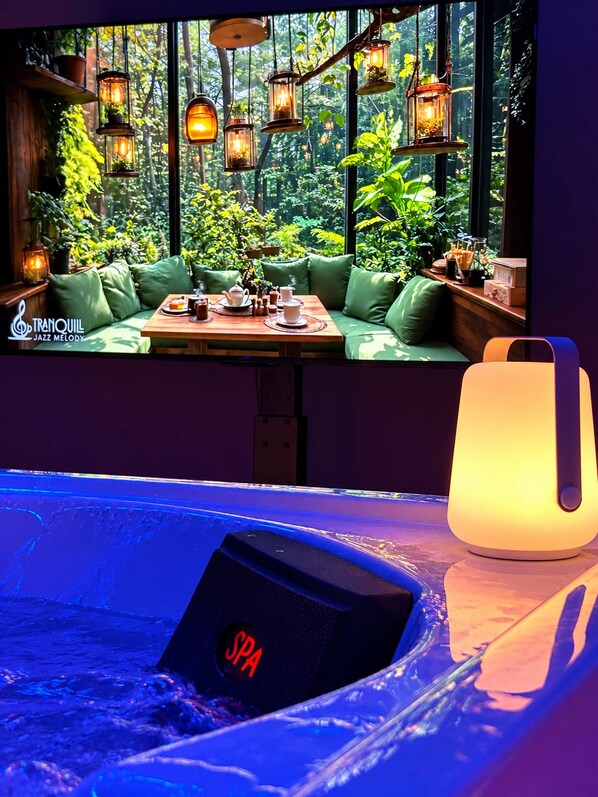 A spa area with a hot tub, a table with tea set, and hanging lanterns.
