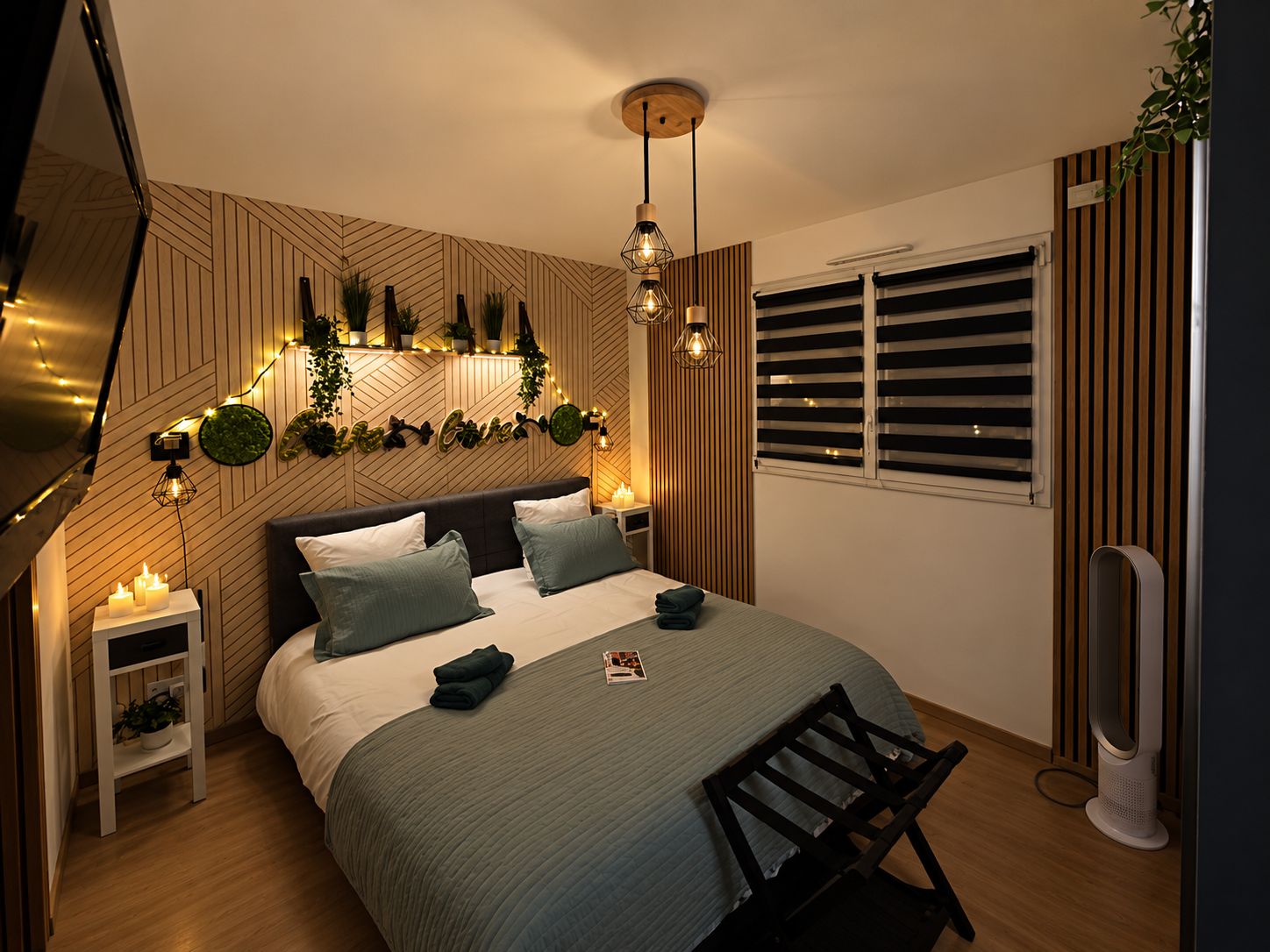 Une chambre moderne avec un lit, des tables de chevet, un luminaire fixé au mur et une fenêtre avec des stores.