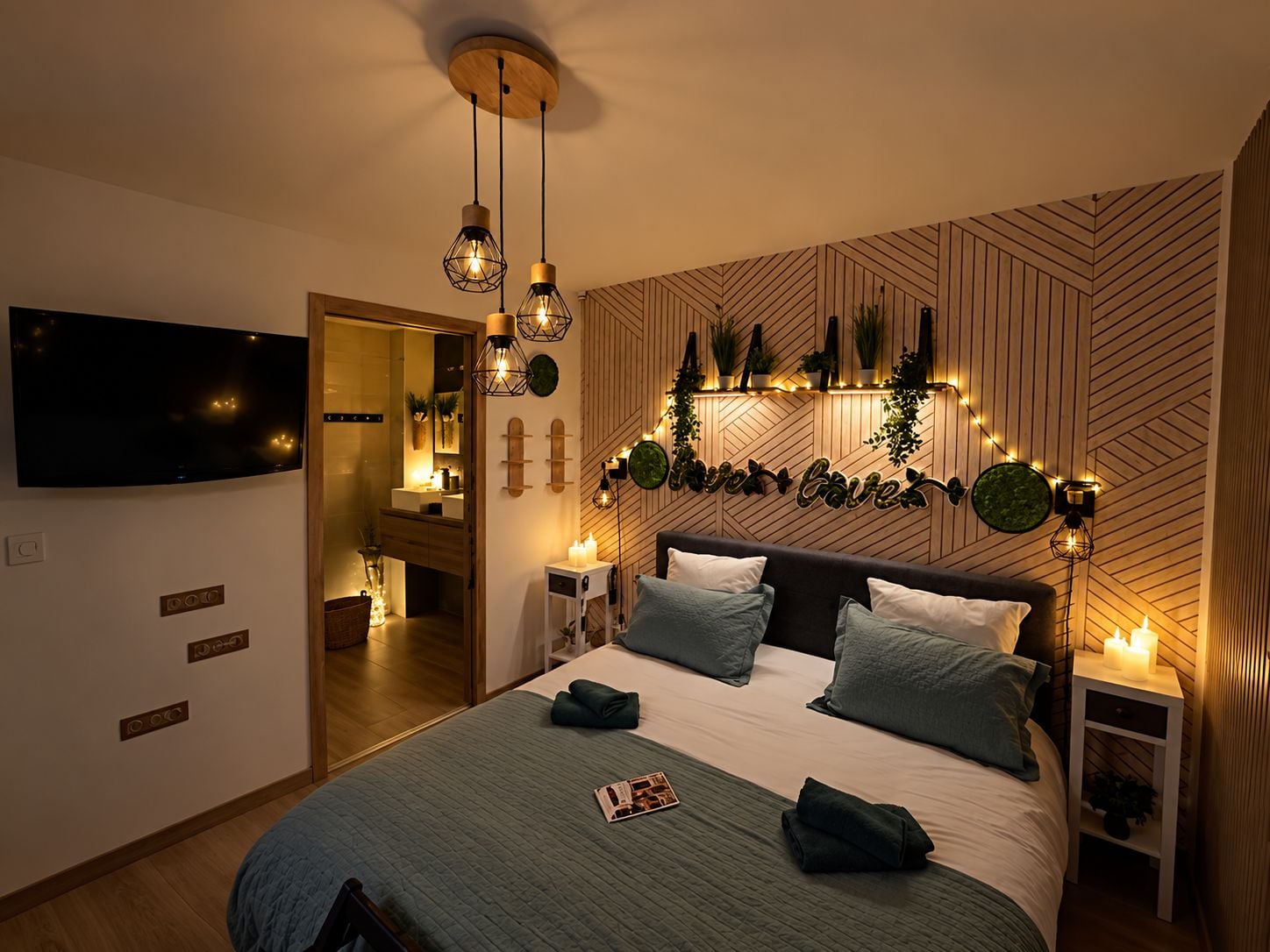 Un dormitorio moderno con cama, mesitas de noche, televisión y un aplique de pared.