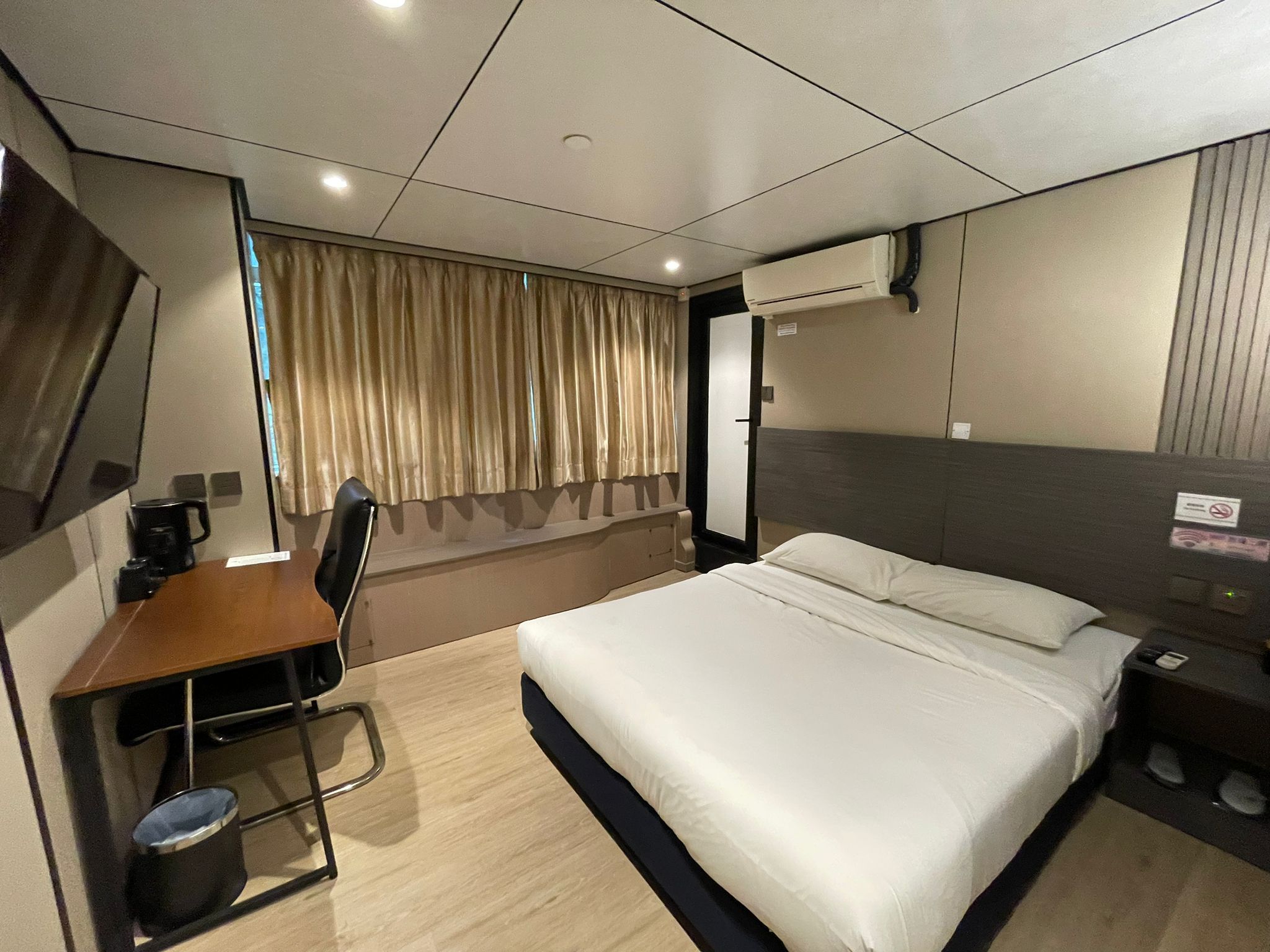 A hotel room with a bed, desk, chair, and a mirror.