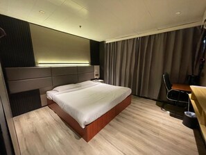 A hotel room with a bed, a desk, and a chair. - Tai Po Inn (N.T)