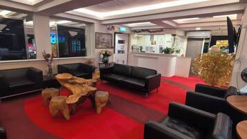 A modern lobby with a red carpet, black leather sofas, and a wooden coffee table.