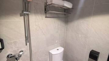 A modern bathroom with a toilet, a shower, and a towel rack.