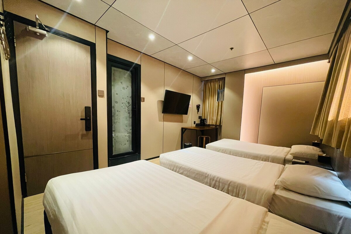 A hotel room with two beds, a television, a desk, and a wardrobe.