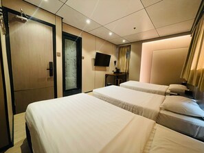 A hotel room with two beds, a television, a desk, and a wardrobe. - Tai Po Inn (N.T)