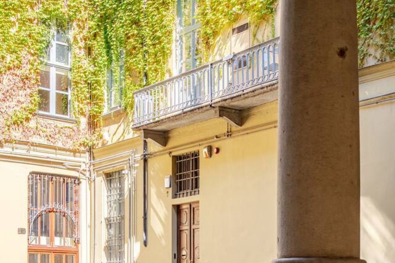 Eine Gebäudefassade mit Balkon, einem vergitterten Fenster und einer Tür.