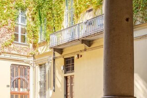 Eine Gebäudefassade mit Balkon, einem vergitterten Fenster und einer Tür.
