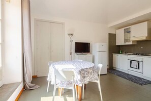 Une cuisine compacte comprenant un coin repas, un téléviseur et un réfrigérateur.