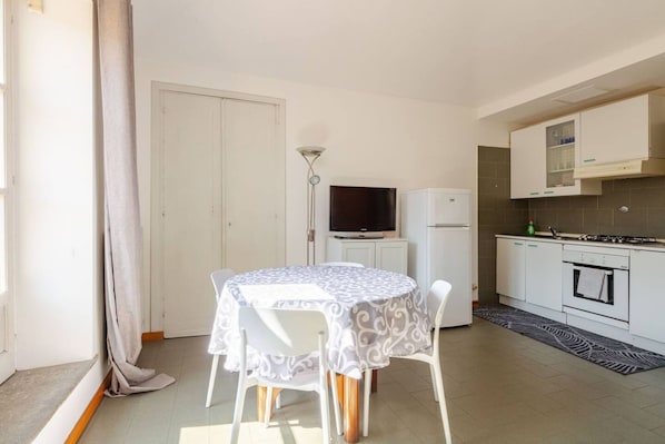 Eine kleine Küche mit Essecke, Fernseher und Kühlschrank.