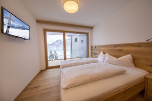 Ein Schlafzimmer mit einem Holz-Kopfteil, einem Bett mit weißer Bettwäsche, einem Nachttisch und einem großen Fenster mit Bergblick.