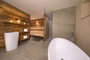 Un bagno moderno con una vasca freestanding, un lavandino e una panca.