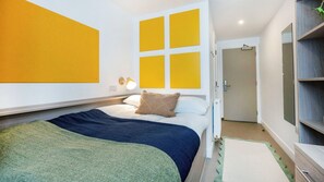 A modern bedroom with a bed, bedside table, and a wall-mounted lamp. - Student Only Timber Yard (Bristol)