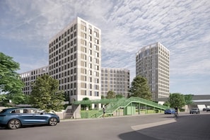A modern building complex with multiple high-rise structures, a pedestrian bridge, and a parking area with vehicles. - Student Only Timber Yard (Bristol)