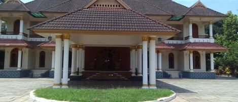 A large, two-story building with a central entrance, flanked by columns, and a tiled roof.