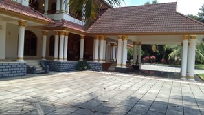A covered outdoor area with a tiled floor, columns with golden accents, and a brick base.