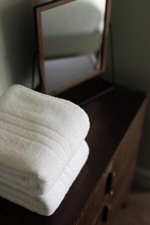 A neatly folded white towel on a wooden dresser. - Family Suite with Bunk Room | Olive House (Ambleside)