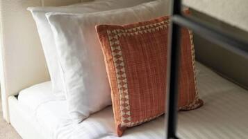 A bunk bed with white bedding and a patterned pillow.