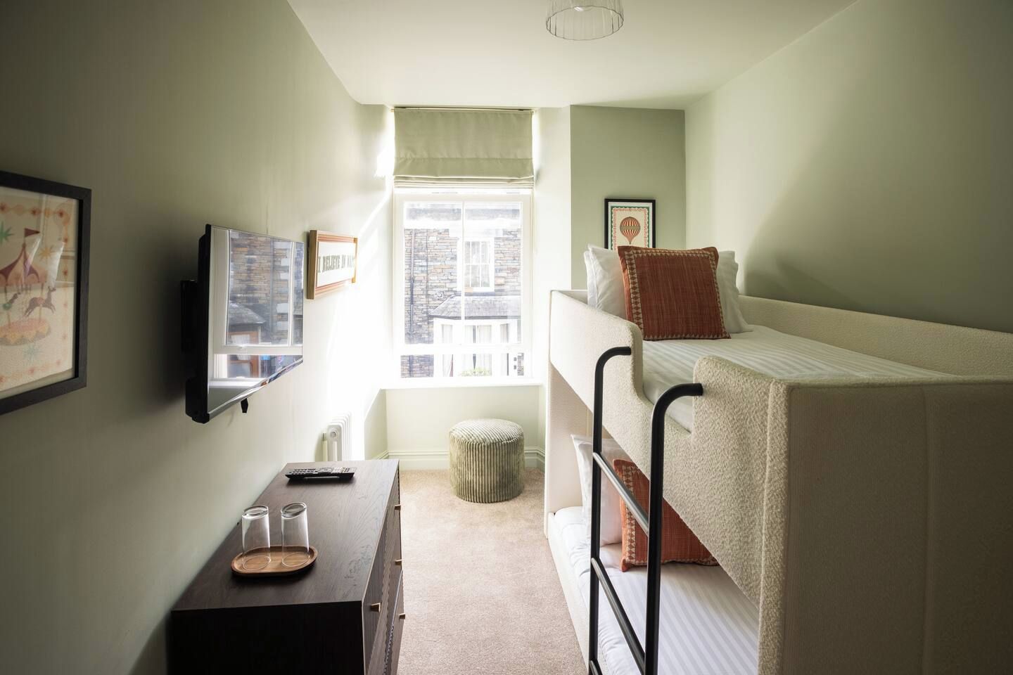 Une chambre de dortoir avec des lits superposés, un bureau avec une chaise, une télévision et une fenêtre donnant sur des immeubles.