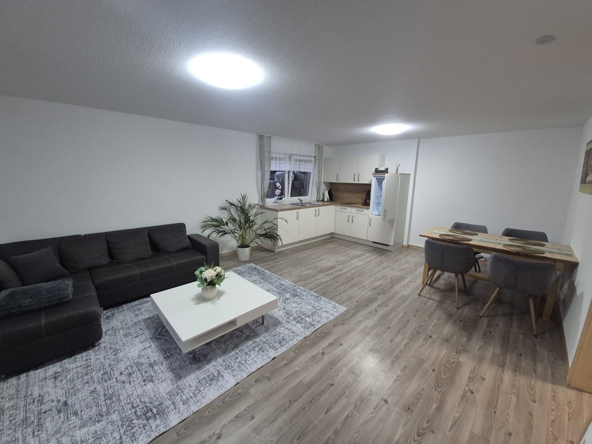 Ein modernes Wohnzimmer mit einer Couch, einem Couchtisch und einem Essbereich mit Tisch und Stühlen.
