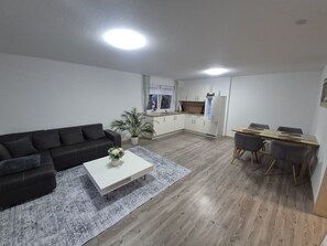 Una sala de estar moderna con un sofá, una mesa de centro y un comedor con mesa y sillas.