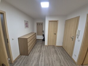 Una habitación con un aparador de madera, un perchero y una puerta.