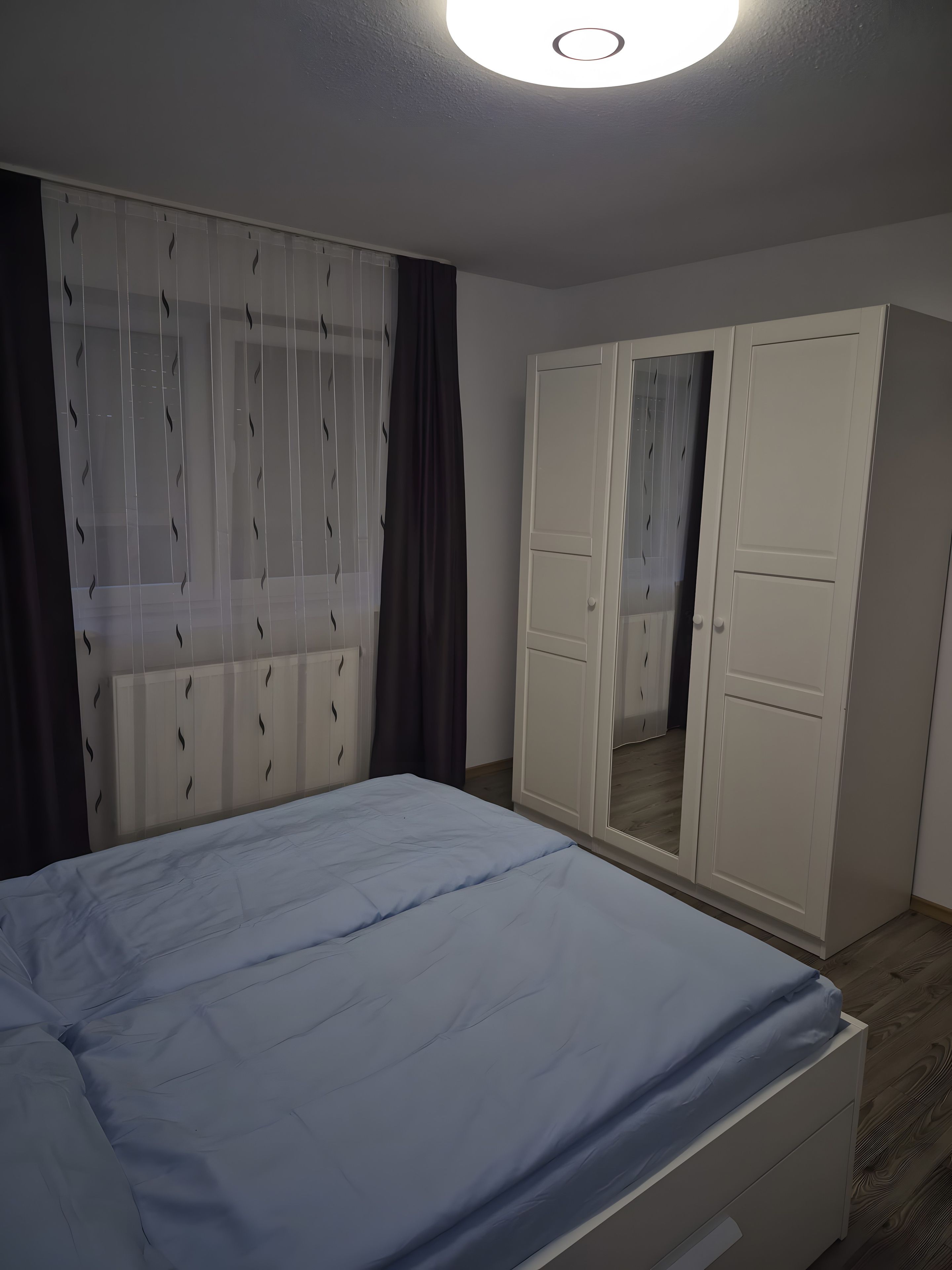 Ein Schlafzimmer mit einem Bett, einem Kleiderschrank und einem Spiegel.