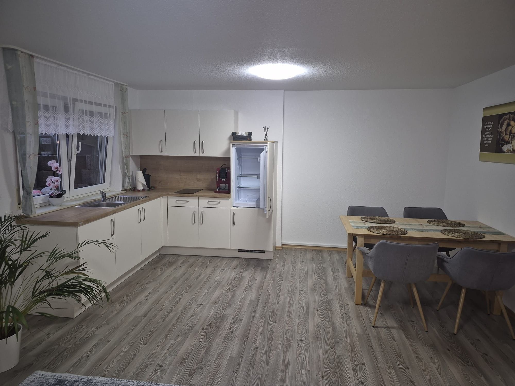A compact kitchen with white cabinets, a built-in oven, and a dining area with a wooden table and chairs.