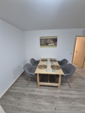 A dining area with a wooden table, four grey chairs, and a wall-mounted picture. - Apartment 'Fewo Kern' with Wi-Fi (Viernheim)