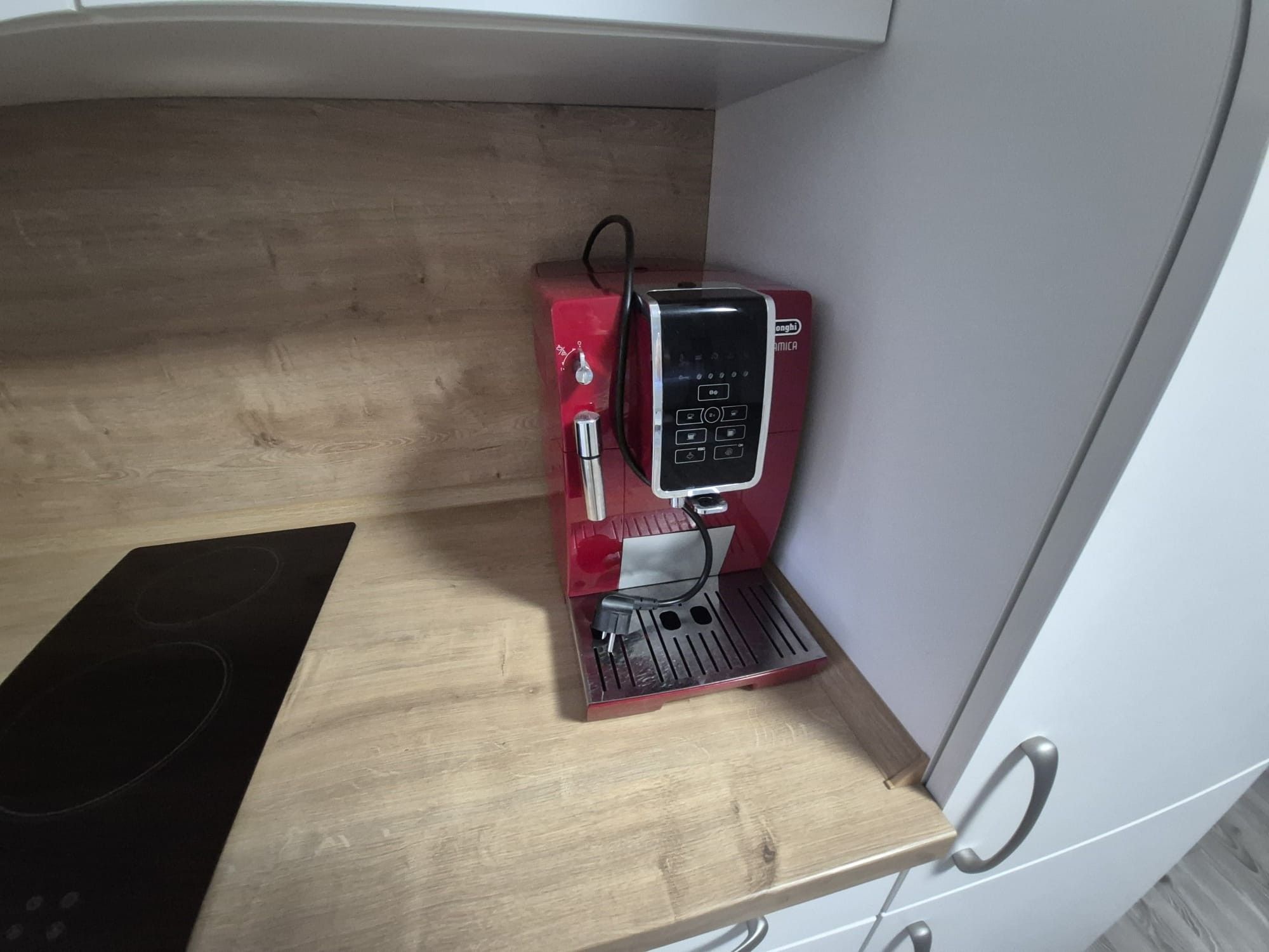 Una cocina compacta con cafetera espresso integrada, una placa de inducción negra y encimera de madera.