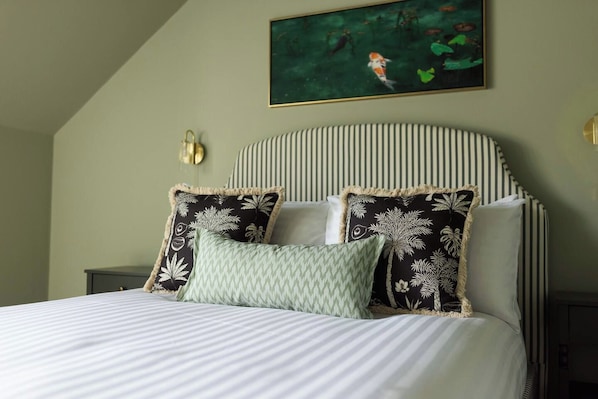 A bed with striped bedding, a headboard with vertical lines, and decorative pillows with leaf patterns.