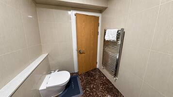 A small bathroom with a toilet, a wooden door, and a towel rack.