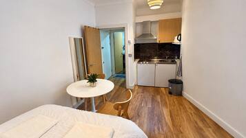 Une chambre à coucher de taille réduite, avec un lit et une petite table sur laquelle est posée une plante.