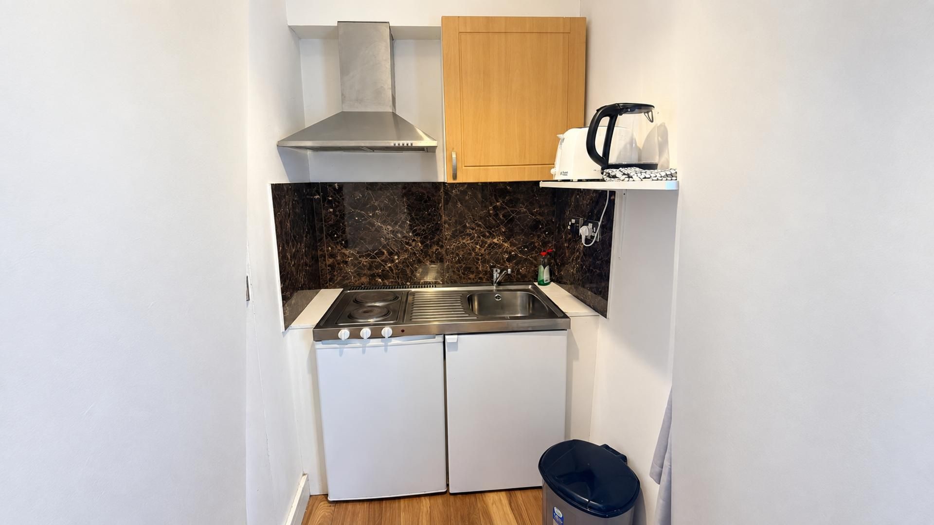 Une petite cuisine équipée avec une cuisinière, un évier et une machine à café, le tout installé sur une étagère.