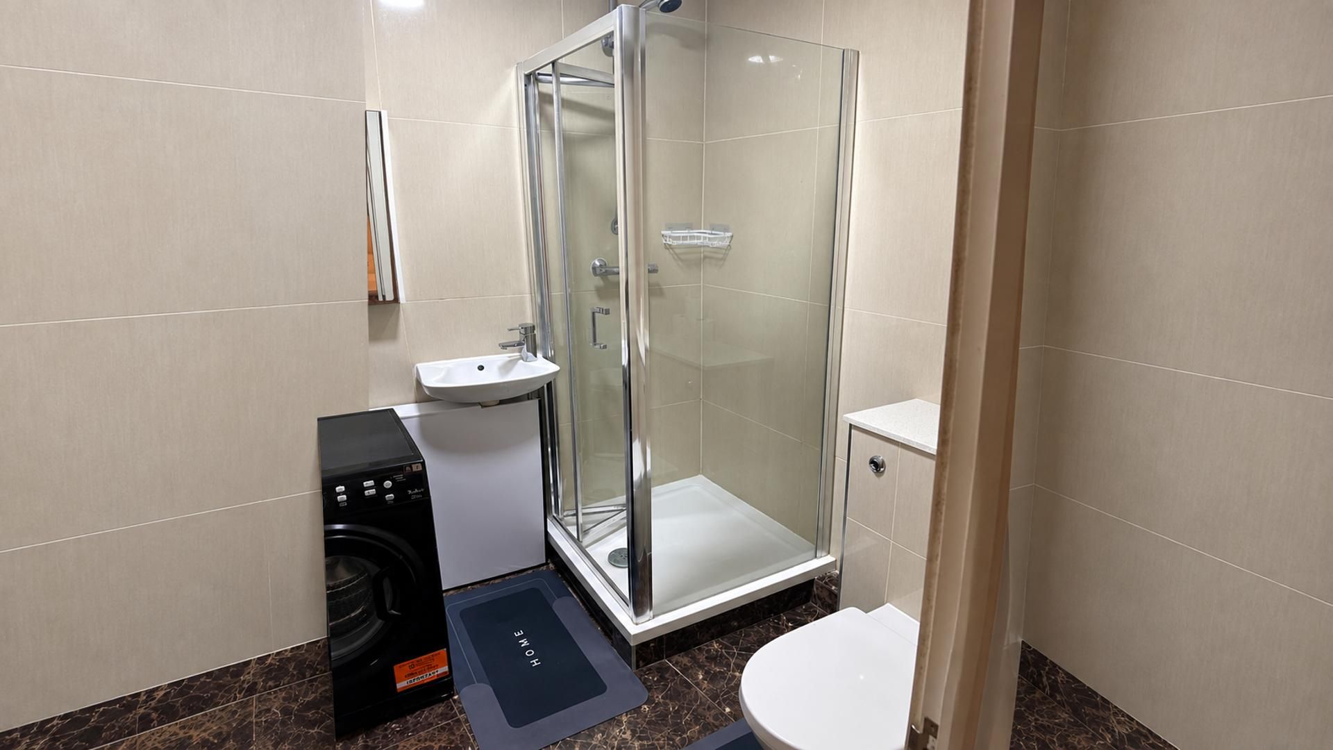 Une salle de bain avec une douche à parois de verre, un lavabo blanc et des toilettes.