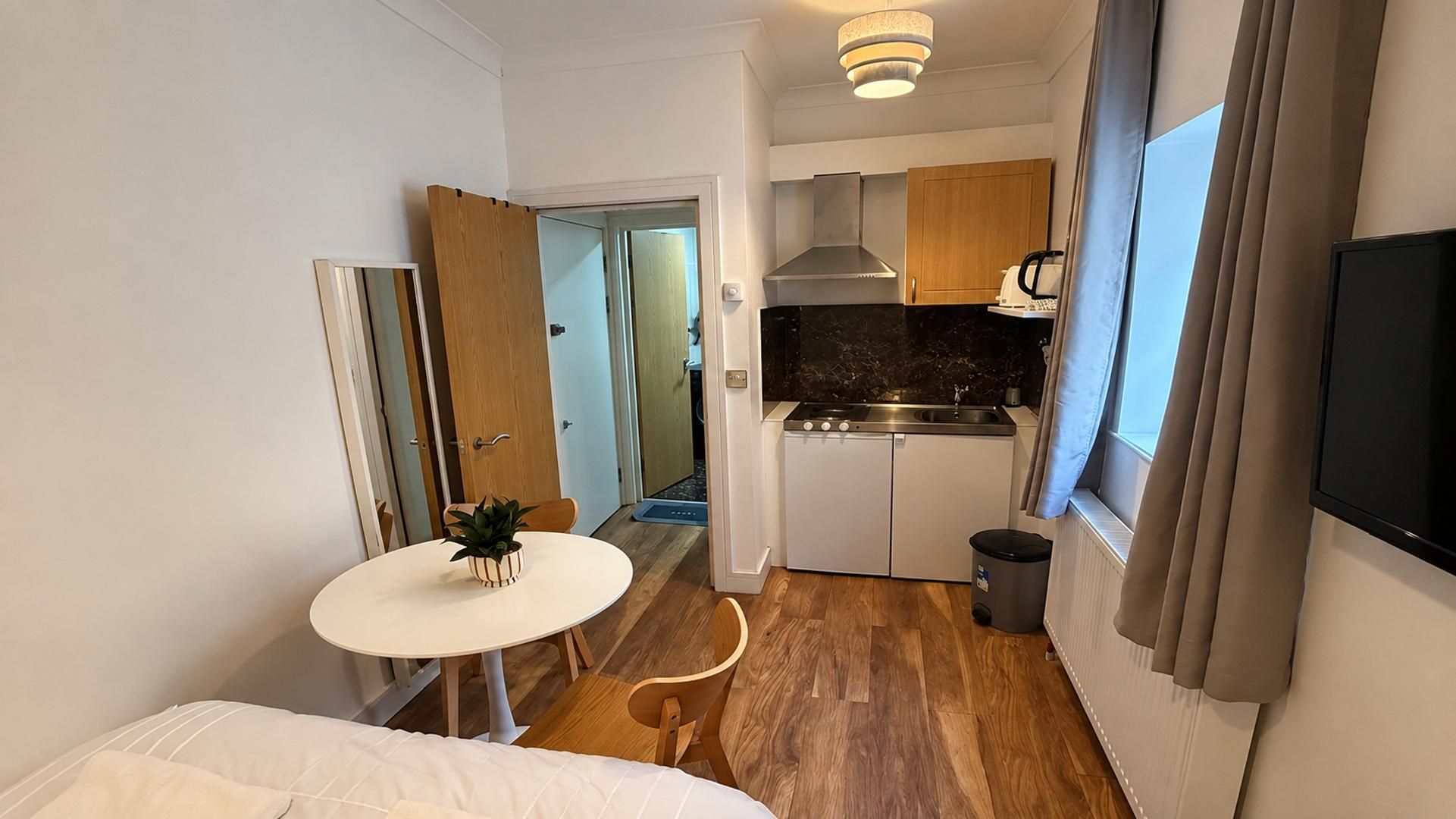 Une chambre d’hôtel compacte comprenant un coin cuisine, un espace repas et un lit.