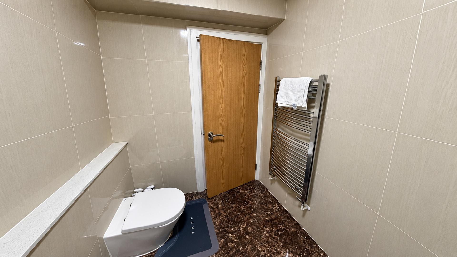 Une petite salle de bain avec des toilettes, une porte en bois et un porte-serviettes.