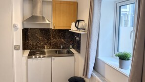 A compact kitchen with a stove, sink, and wooden cabinets. - Acton 1-bed Apt, Sleeps 2 Near Rosemont Rd Station (London)