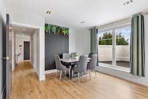 A dining area with a table and chairs, a view of the outdoors, and a wooden floor. - 2bedroom 2bathroom Penthouse Wembley Stadium (Wembley)