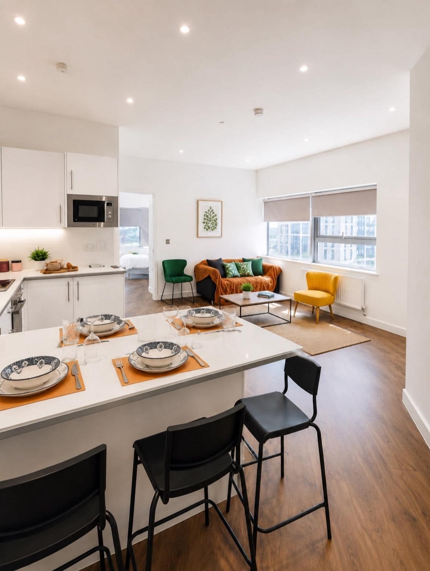 A modern kitchen with white cabinets, a microwave, and a dining area with a table set for two.