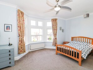 Ein Schlafzimmer mit einem hölzernen Bett, einem Schminktisch, einer Heizung und einem Deckenventilator.