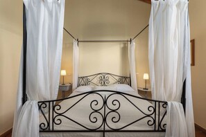 Ein Himmelsbett mit Metallgestell und weißer Bettwäsche.
