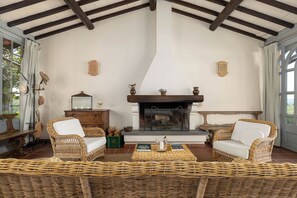 Um quarto aconchegante com lareira, móveis de vime e vista pela janela.