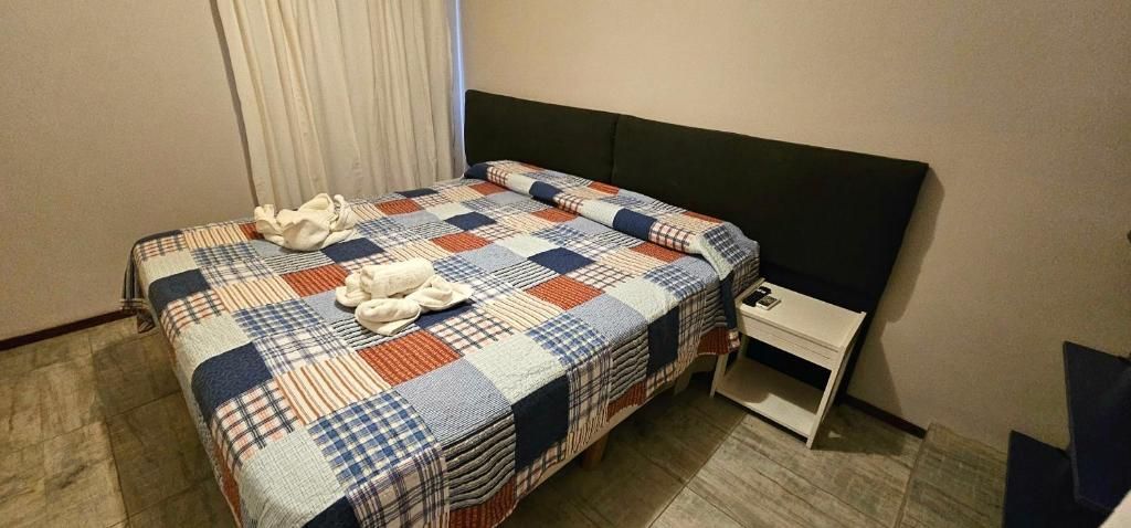 A hotel room with a bed, a nightstand, and a drawer unit.