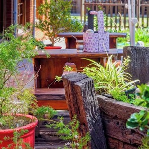 A wooden deck with potted plants and a rustic outdoor seating area. - Hotel Cheval Blanc (Villa Gesell)