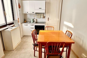 A compact kitchen with white cabinets, a small countertop, and a dining table with four chairs. - Stunning apartment for two, just steps from Parco del Valentino – Turin. (Turin)